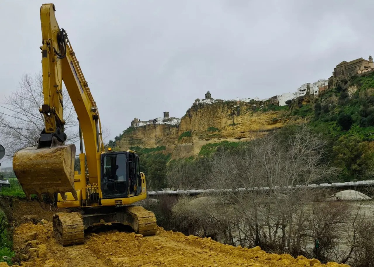 Maquinaria trabajando con Arcos de la Frontera al fondo